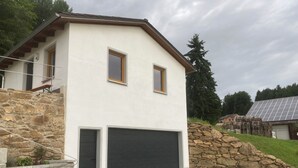 Une maison moderne à deux étages, dotée d’une façade en pierre, d’un garage et d’un ensemble de panneaux solaires à l’arrière.