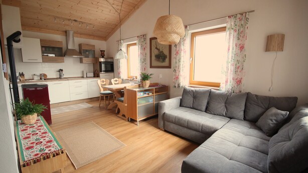 Une cuisine moderne avec des meubles blancs, un réfrigérateur rouge et un coin repas comprenant une table et des chaises en bois.