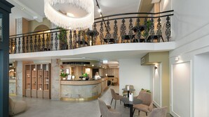 A spacious lobby with a reception desk, seating area, and a balcony with decorative railings. - CHLOE Hotel Budapest (Budapest)