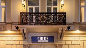 The entrance of the Chloe Hotel Budapest with a classic facade, ornate balcony, and illuminated signage. - CHLOE Hotel Budapest (Budapest)