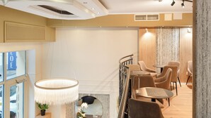 A modern interior with a staircase, seating area, and a view of the street. - CHLOE Hotel Budapest (Budapest)
