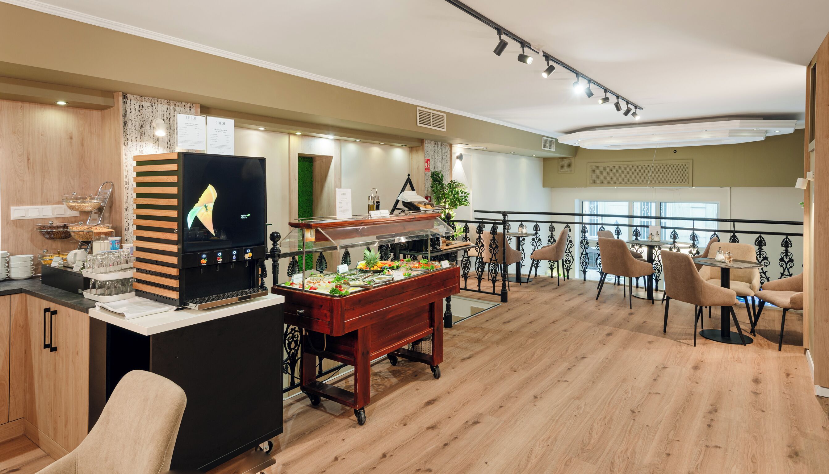 A buffet area with a digital menu display, a variety of food options, and a seating area with chairs and tables.