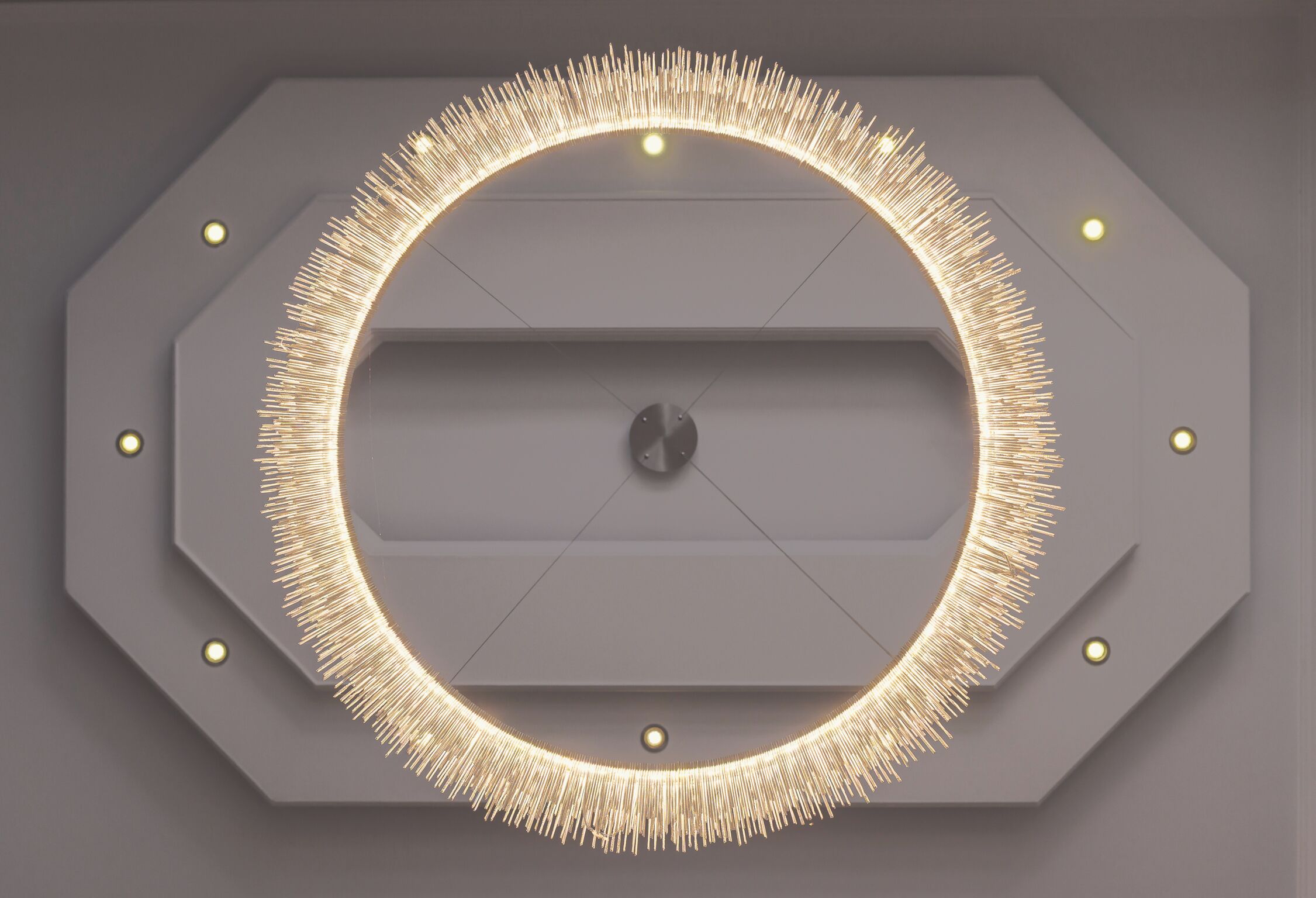 Diseño moderno y geométrico del techo, con un elemento circular central y lámparas circundantes.