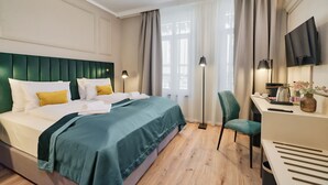 A hotel room with a bed, a desk, a chair, a TV, and a window with curtains. - CHLOE Hotel Budapest (Budapest)