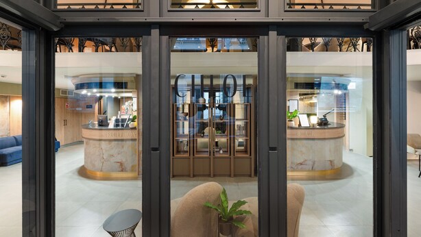 A modern hotel lobby with a reception desk, a bar area, and a seating area with a potted plant. - CHLOE Hotel Budapest (Budapest)