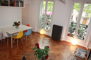 Zona pranzo con tavolo bianco, sedie colorate e pavimento in legno a spina di pesce.
