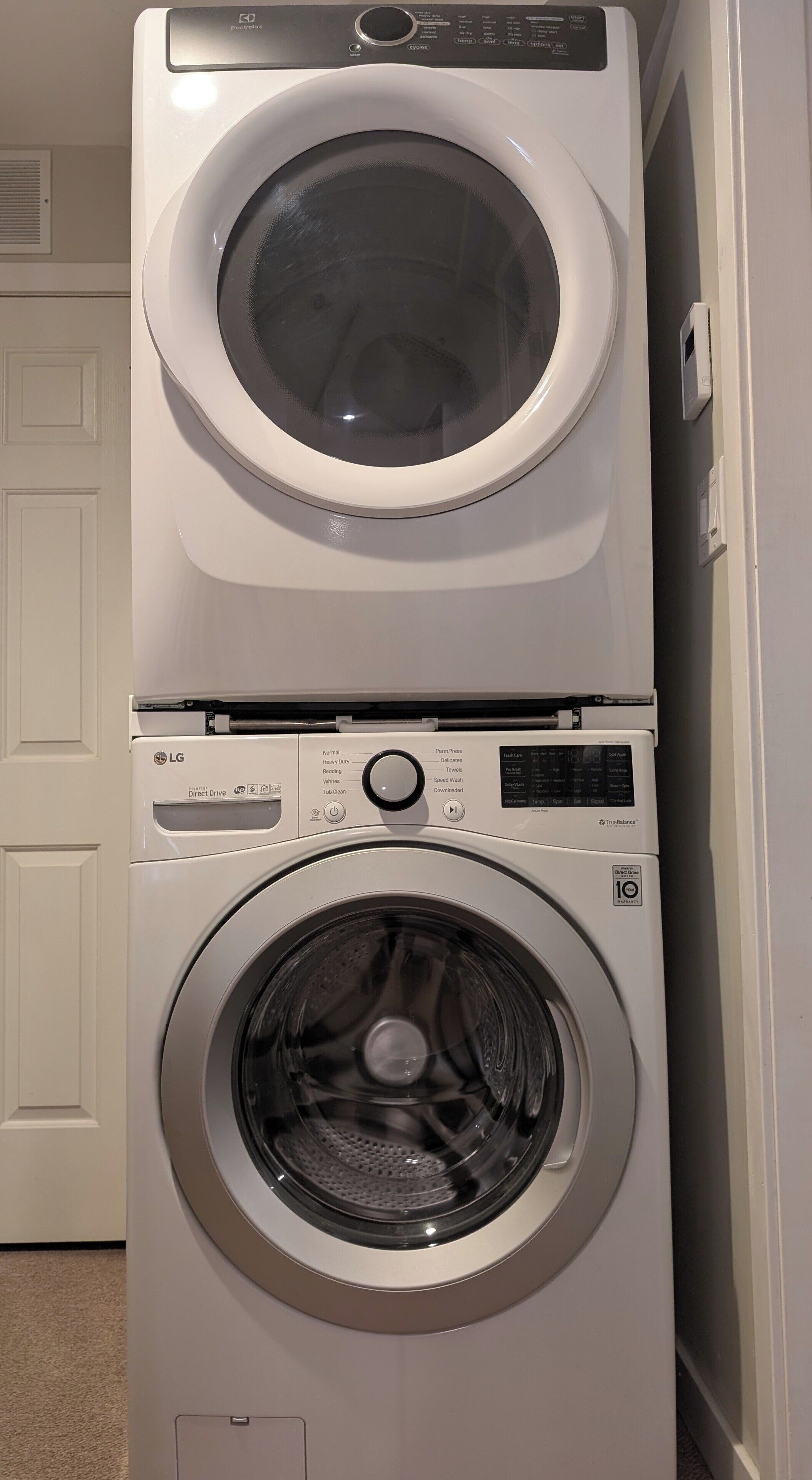 En tvätt- och torkmaskin som är placerad ovanpå varandra, med en kontrollpanel, en lucka och ett ventilationsutlopp.