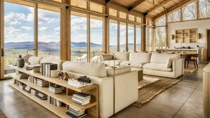 Ein geräumiges Wohnzimmer mit großem Fenster und Blick auf die Berge, einer eingebauten Bücherwand und einer gemütlichen Sitzecke.