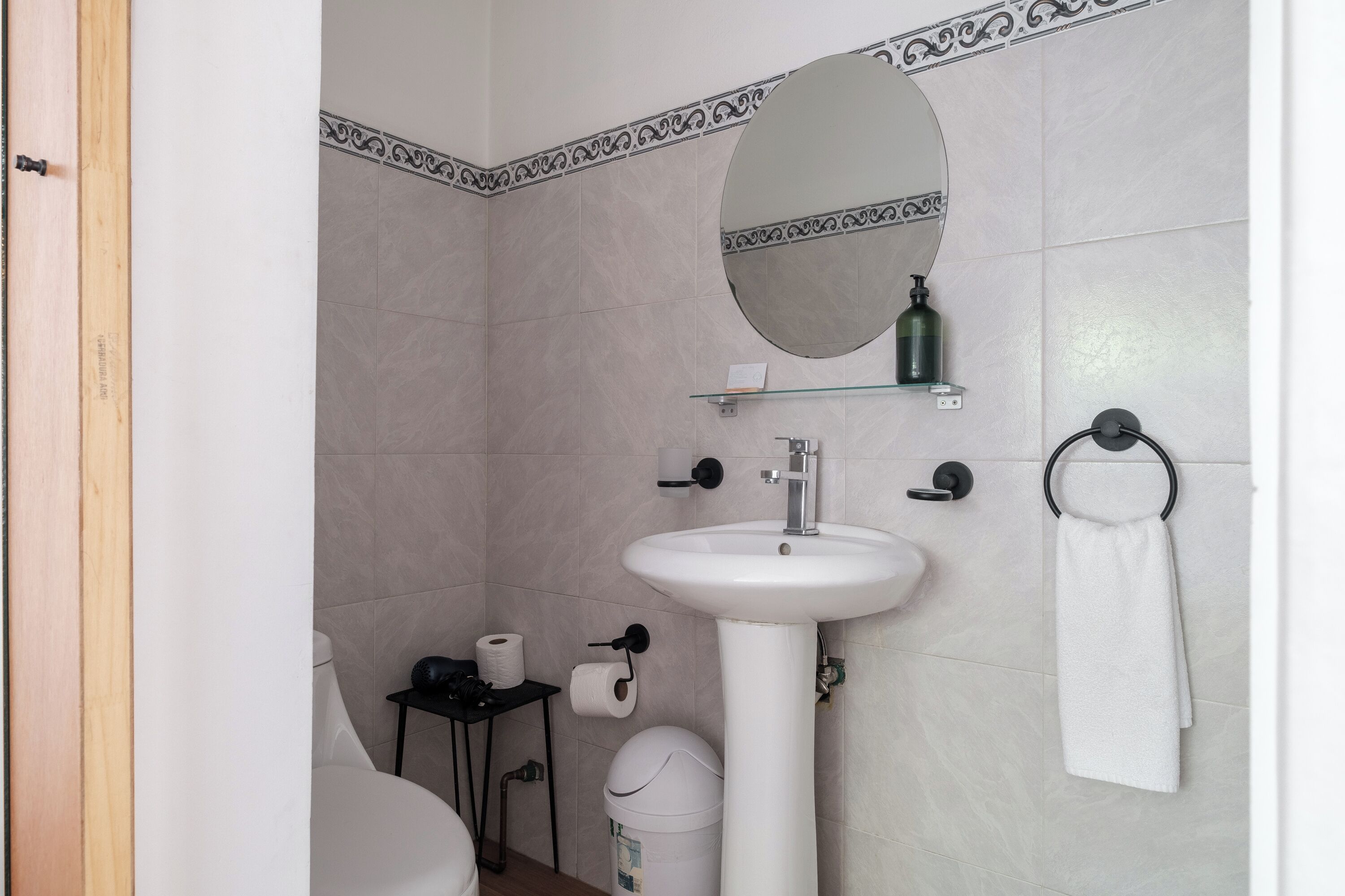 Une salle de bain avec un lavabo blanc, un miroir, un porte-serviettes et des toilettes.