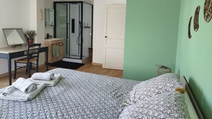 Une chambre avec un lit, un bureau, une chaise, une douche et un mur vert.