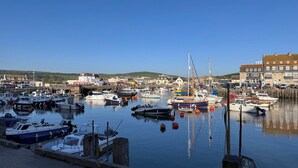 Un port de plaisance où sont amarrés différents types de bateaux, un pont et des bâtiments en arrière-plan.
