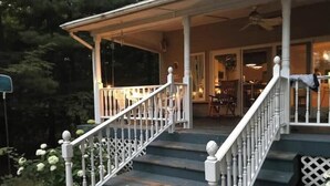 Un escalier en bois, avec des balustrades blanches, mène à un porche abrité.