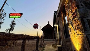 A rustic building with a 'Hotel Vacancy' sign, a 'No Entry' sign, and a small structure in the background. - Lone Ranger RV Park & Lodge (Ranger)