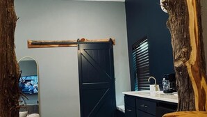 A room with a wooden-framed view, a black door, a white sink, and a small rug. - Lone Ranger RV Park & Lodge (Ranger)