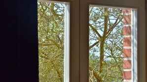 Two windows with a view of a tree and a brick wall. - Complete guesthouse on the Finow Canal (former school from 1875) for 12 people (Wandlitz)