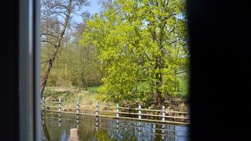 A view of a pond with a wooden fence and trees in the background.