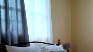 Una cama bien hecha con ropa de cama blanca y azul, un cabecero de madera y una mesita de noche con una lámpara.