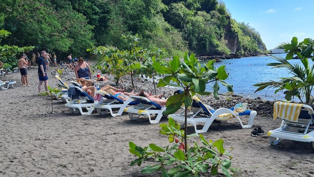Una playa con tumbonas y un litoral rocoso.