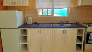 Una cocina con gabinetes blancos, un lavamanos, una estufa y un refrigerador.