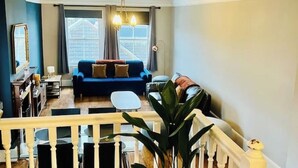 A living room with a blue sofa, a small table, and a staircase leading to another floor. - Richmond charm cozy apartment (Richmond)