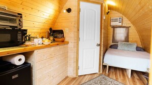 Una cabaña acogedora con kitchenette, una cama y una puerta que da a otra habitación.