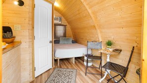 Un dormitorio acogedor en el ático, con cama, una mesita y una silla.