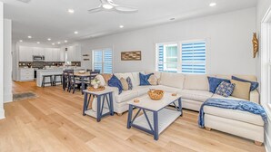 Uma sala de estar ampla com um sofá grande, uma mesa de centro e um espaço de jantar com cadeiras.