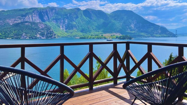 A wooden deck with two chairs overlooking a lake and mountains. - FjordCabin Preikestolen (Rogaland)