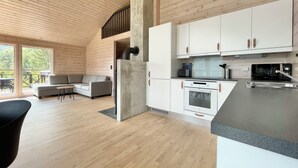 A modern log cabin interior with a kitchen, living area, and a balcony. - FjordCabin Preikestolen (Rogaland)