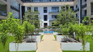 A modern building with a central courtyard featuring a pool, surrounded by greenery and concrete planters. - premier luxury apartment (Accra)