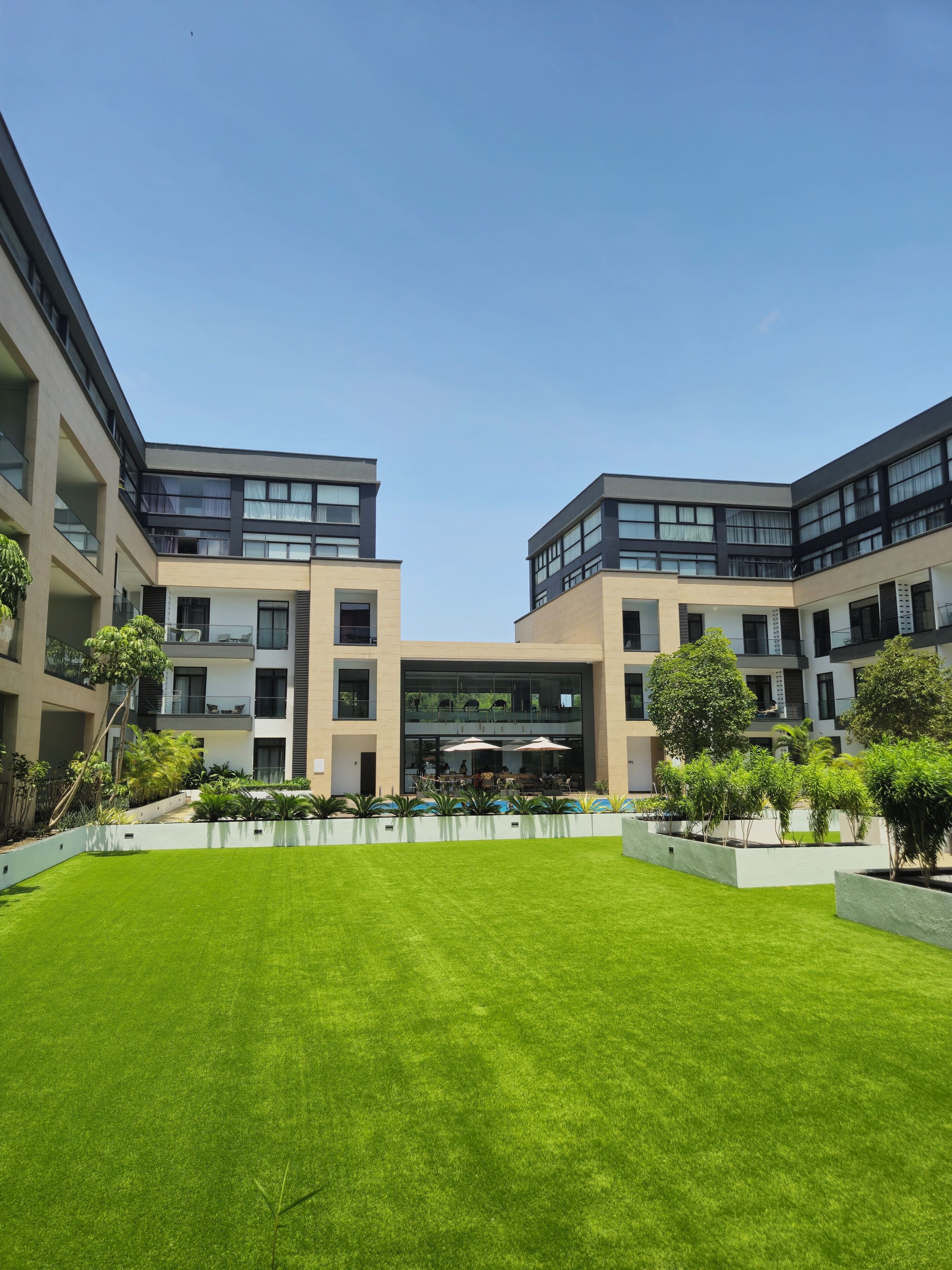 Un edificio moderno con un patio que cuenta con un césped cuidado y una zona de estar al aire libre.