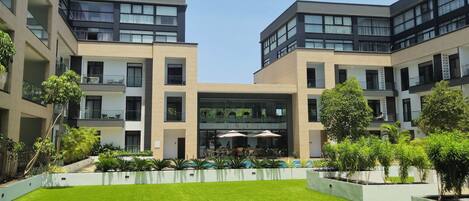 Un edificio moderno con un patio que cuenta con un césped cuidado y una zona de estar al aire libre.