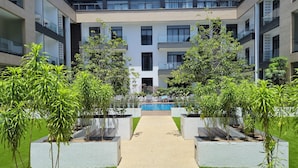 A modern building with a central courtyard, a swimming pool, and surrounding greenery. - premier luxury apartment (Accra)