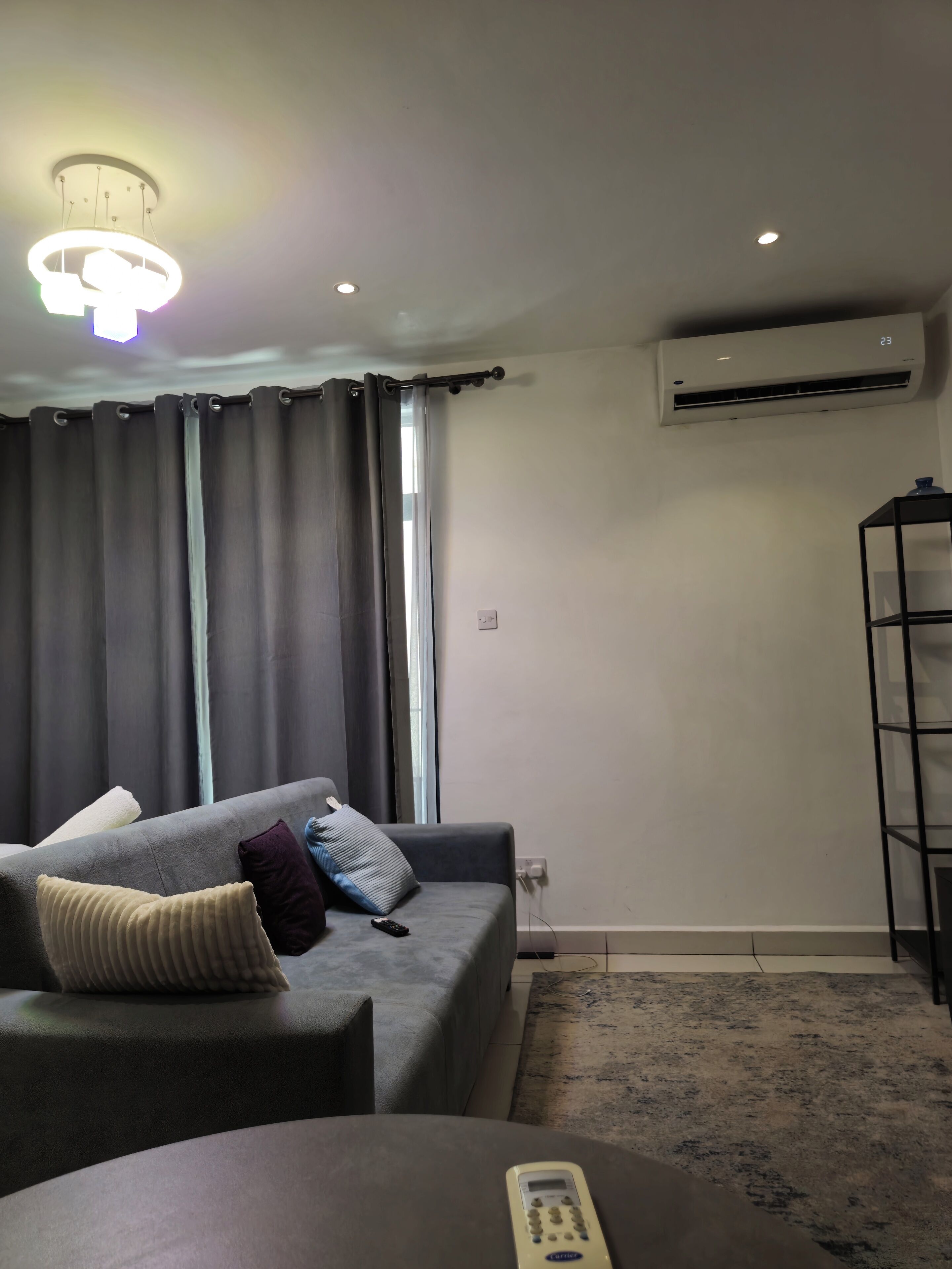 A modern living room with a grey sofa, a remote control, and a small table.
