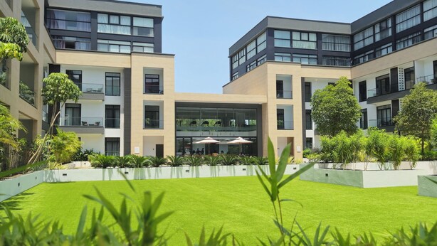 A modern building with a central courtyard, surrounded by greenery and featuring multiple balconies. - premier luxury apartment (Accra)
