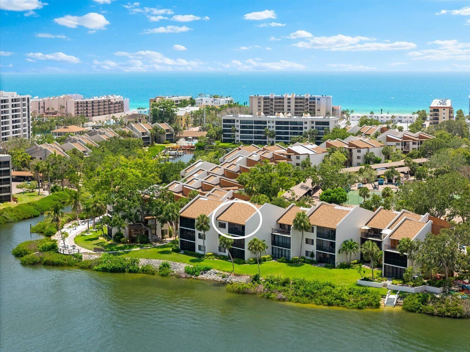 Un hotel frente al mar con varias construcciones, un puerto deportivo y vistas al océano.