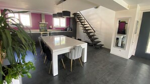 Une cuisine moderne avec un îlot central blanc, un revêtement de sol foncé et un escalier en colimaçon menant à un niveau supérieur.