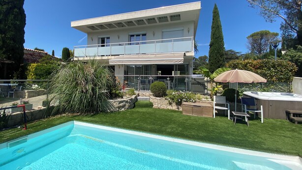 Une maison moderne à deux étages avec une piscine en premier plan.