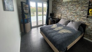 Une chambre à coucher avec un lit, un bureau, une bibliothèque et un mur décoré d’un motif en briques.