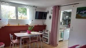 Une pièce comprenant une table à manger, des chaises, un téléviseur, un coin cuisine et un lit.