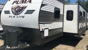 A PUMA XLE Lite RV with a visible license plate, a side door, and a window. - Up North in Comfort – Your Dream Camper Getaway! (Roscommon)