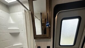 A compact bathroom with a bathtub, sink, and toilet. - Up North in Comfort – Your Dream Camper Getaway! (Roscommon)