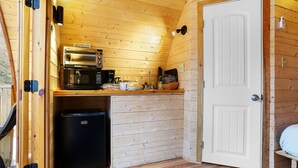 Een kleine keuken met een magnetron, koffiezetapparaat en een spoelbak.
