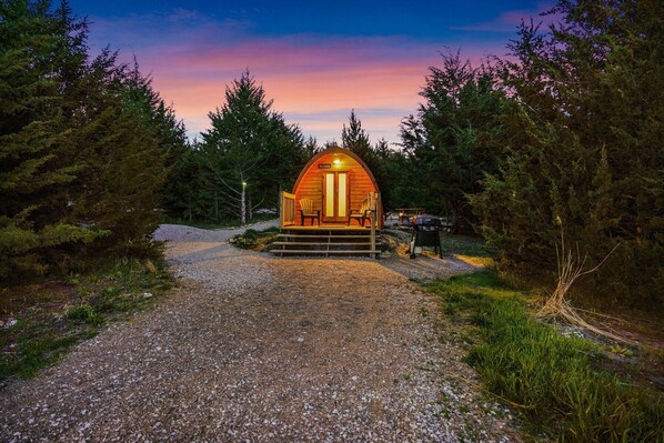 A cozy cabin with a wooden exterior and a porch, surrounded by dense forest.