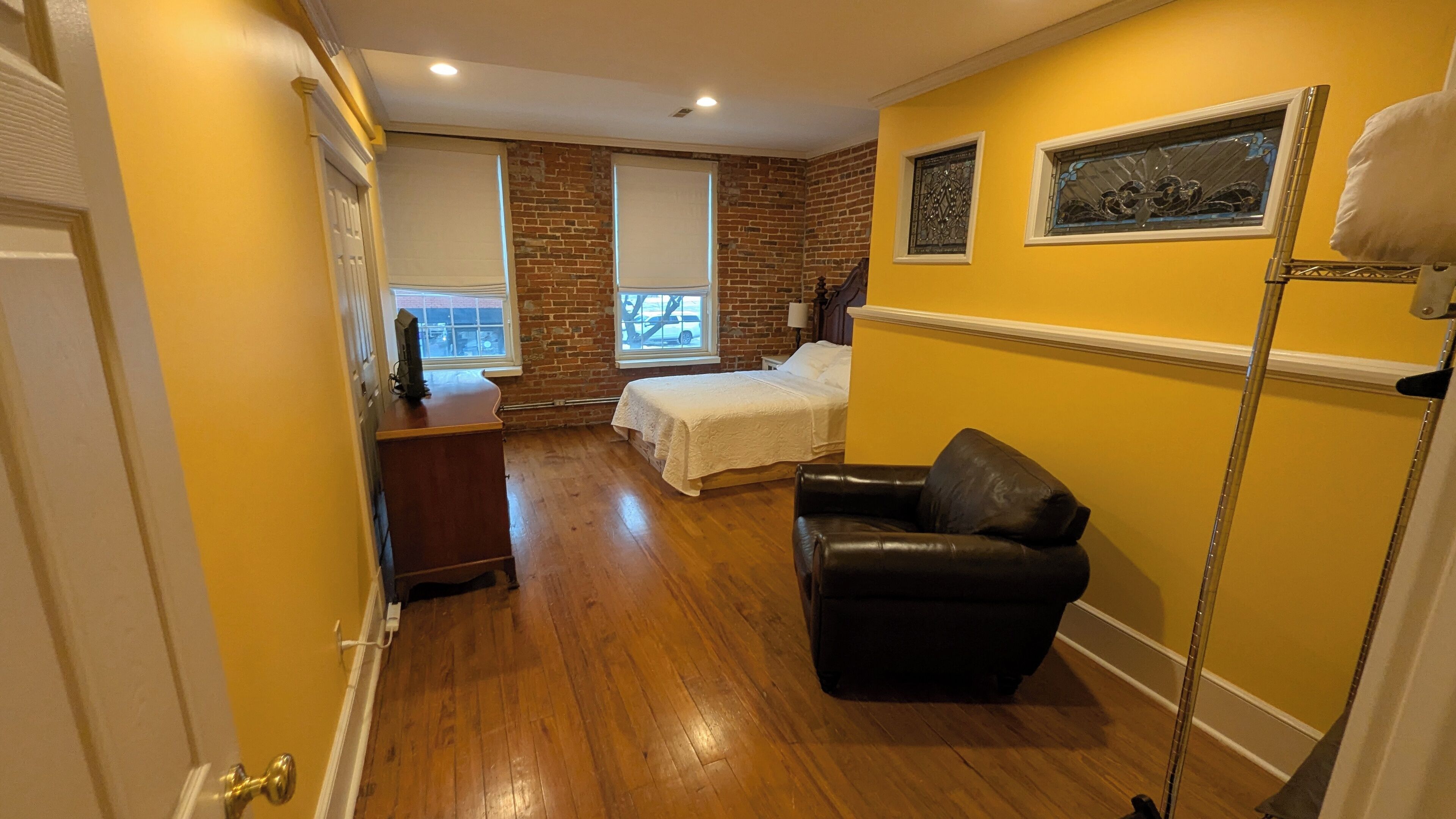 A room with a bed, a desk, a chair, and a window with a view of the outside.