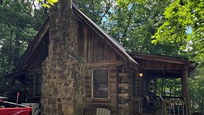 A rustic cabin with a stone chimney, a porch with a wooden railing, and a red truck parked nearby. - Serene cabin with dock/swim platform in charming Speedwell (Speedwell)