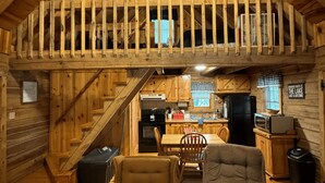 A cozy cabin interior with a loft bedroom, wooden walls, a kitchen, and two plush armchairs. - Serene cabin with dock/swim platform in charming Speedwell (Speedwell)