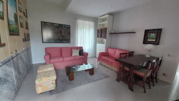 Relax in this stylish living room with a sofa, ottoman, and dining table.