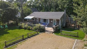 A two-story house with a covered patio, a fenced yard, and a gravel driveway.