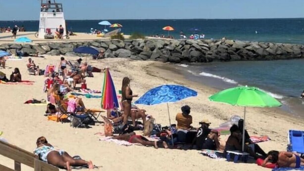 A beach with people sunbathing and relaxing under umbrellas.